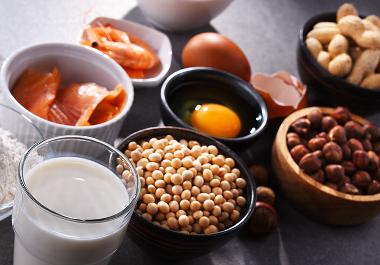 Selection of common foods on a table including milk, nuts, egg, fish and more