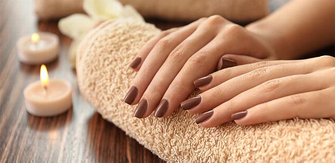 Hands resting on towel on table. nails painted a deep brown
