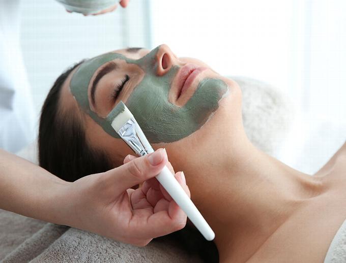 Lady having green face mask applied at spa
