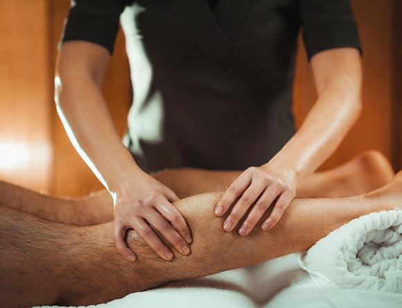 Man at clinic having deep tissue leg sports massage